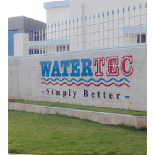 Exterior wall with the sign 'WATERTTEC Simply Better' in blue and red letters above a green lawn.
