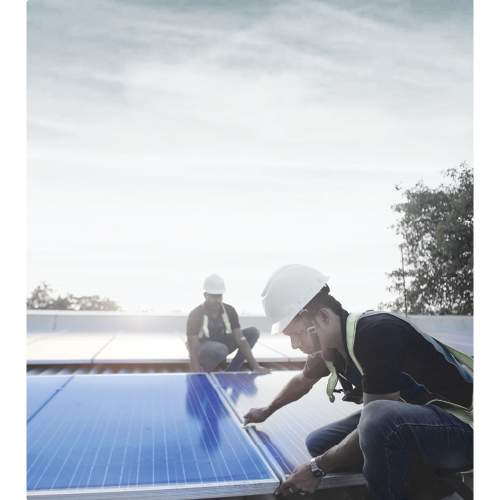 Two workers wearing white helmets and safety vests installing solar panels outdoors under a bright sky.