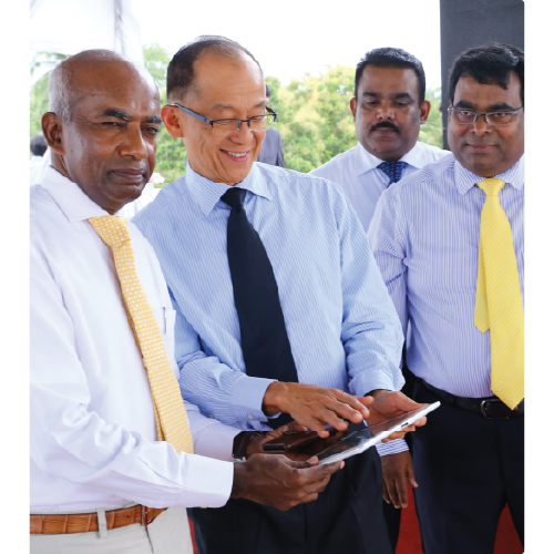 Four businessmen in dress shirts and ties gathered, with two men holding and interacting with a tablet device.